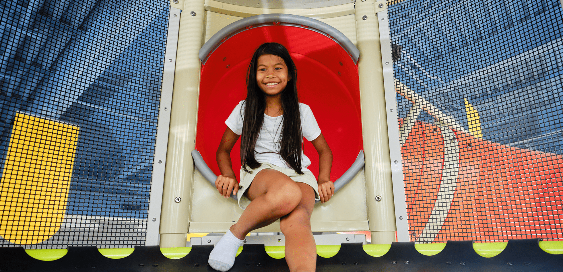 New Heights Tower with an orange spiral slide, girl sitting at the top of the slide